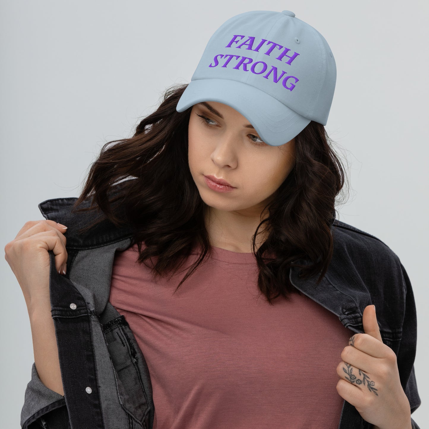 Person is wearing a Faith Strong light blue cap β bold Christian statement hat with purple embroidery, adjustable unisex design by ReBirth Living