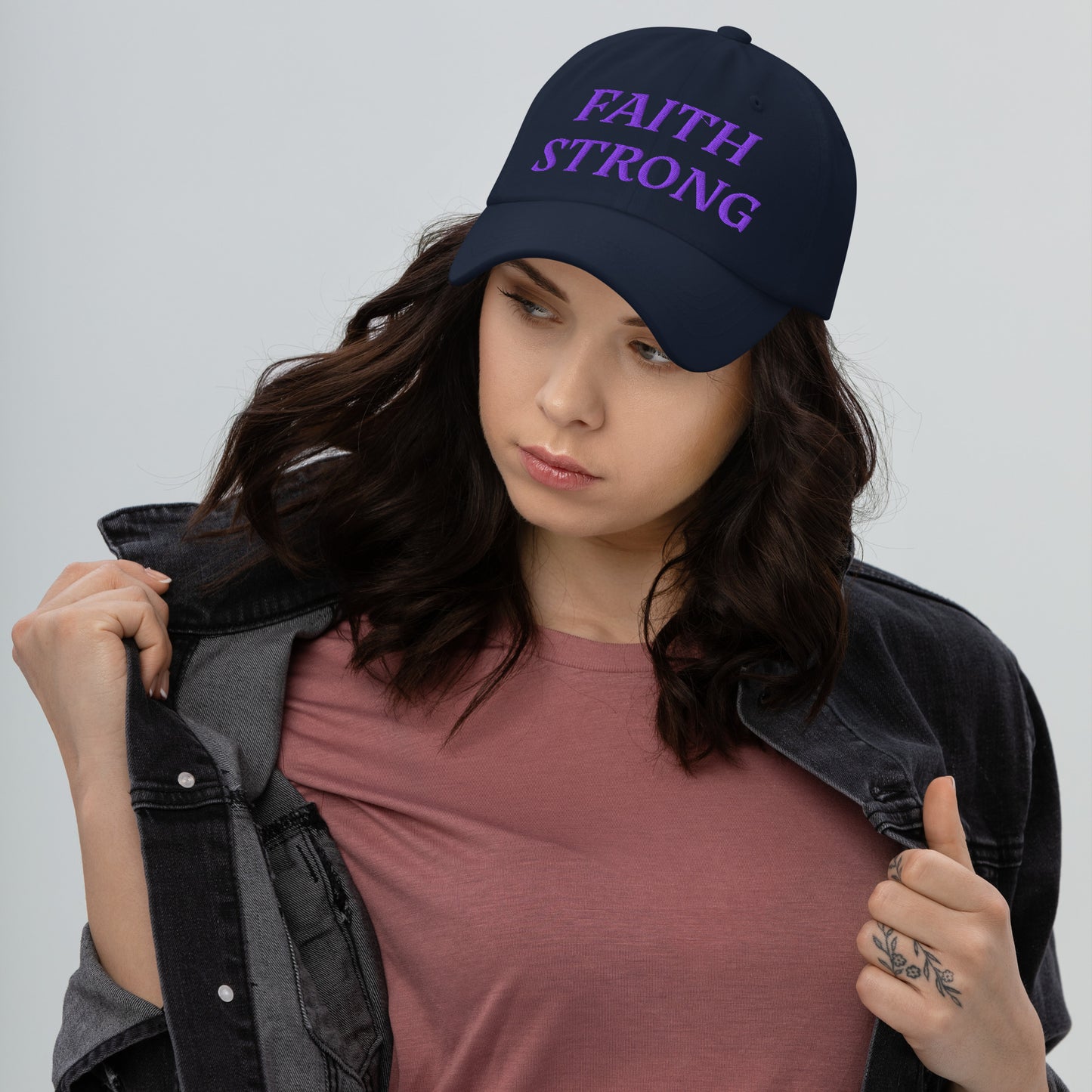 Person is wearing a Faith Strong navy cap β bold Christian statement hat with purple embroidery, adjustable unisex design by ReBirth Living