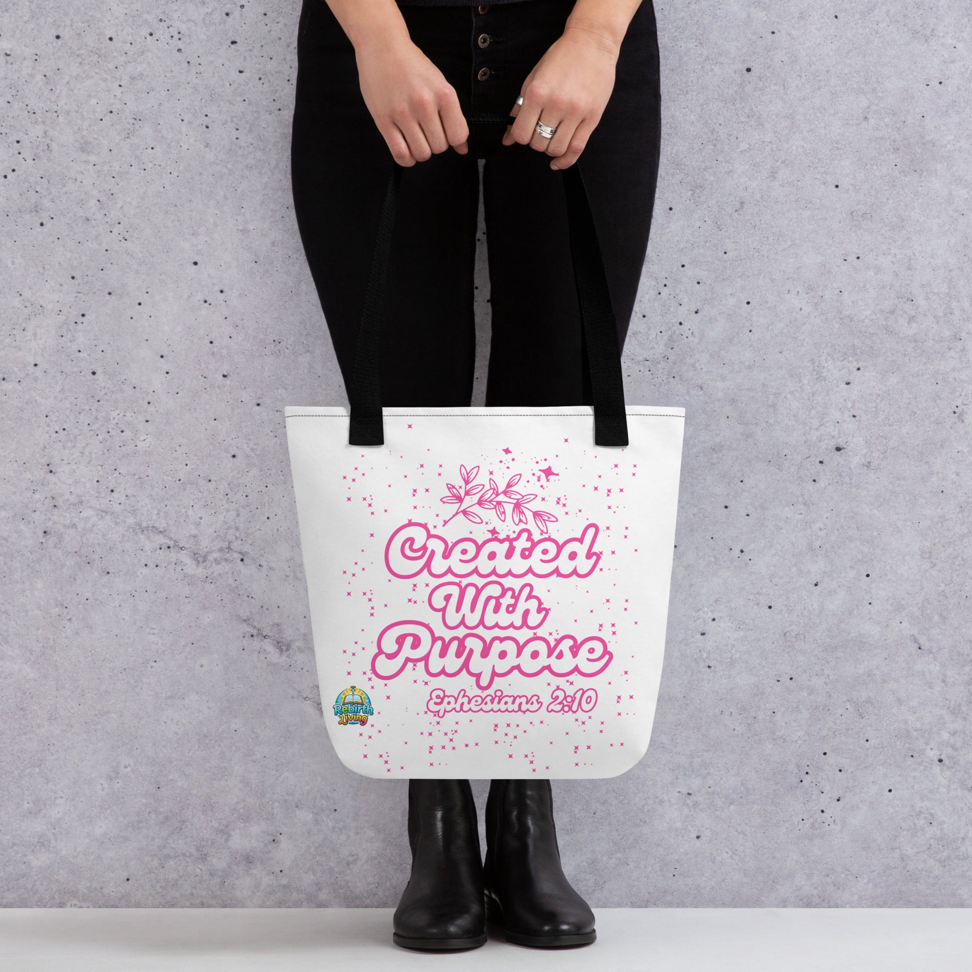 A person holding a Created with Purpose Christian tote bag (15x15) – Ephesians 2:10 KJV scripture design, reusable cotton carryall with a black handle by ReBirth Living