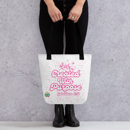 A person holding a Created with Purpose Christian tote bag (15x15) – Ephesians 2:10 KJV scripture design, reusable cotton carryall with a black handle by ReBirth Living