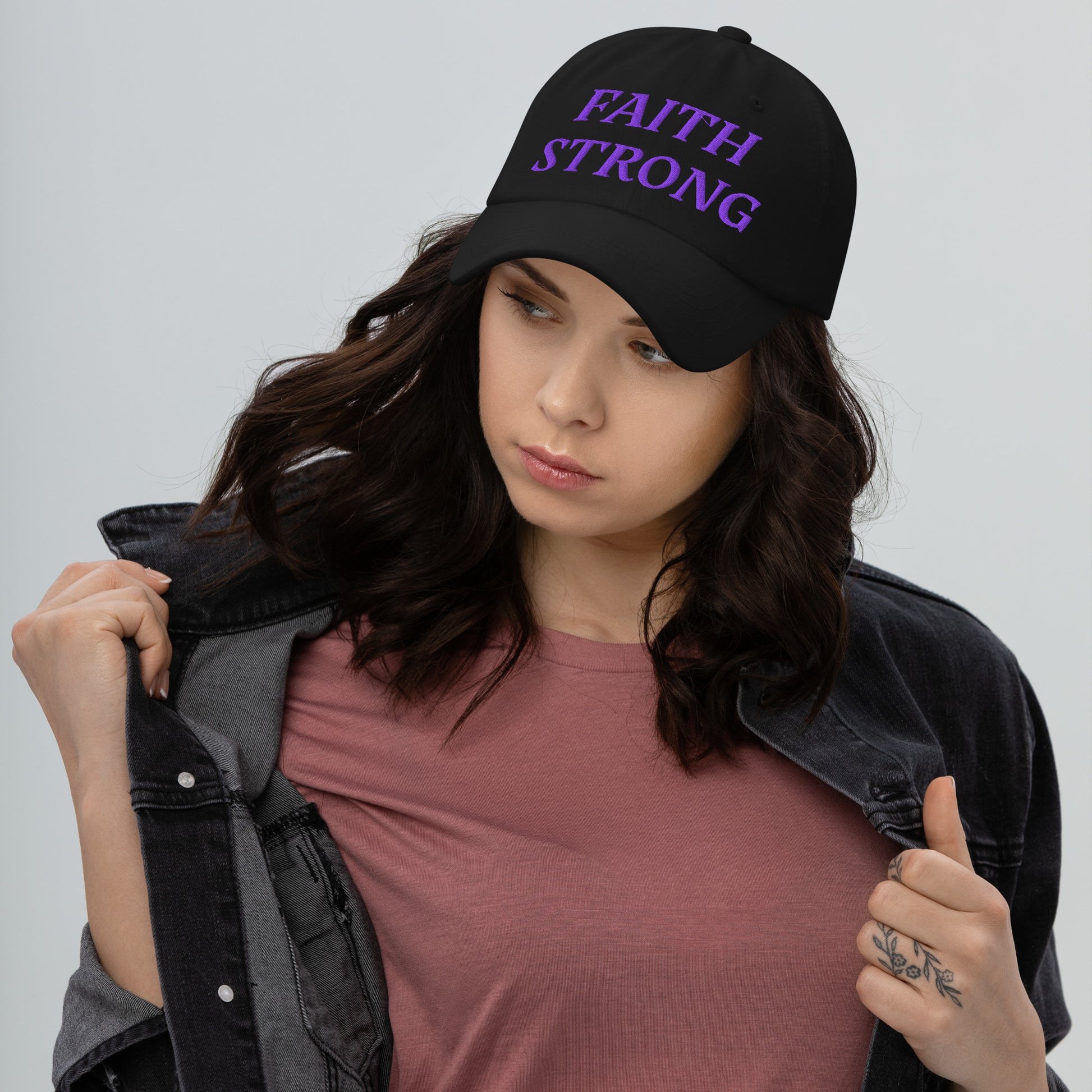 Person is wearing a Faith Strong black cap – bold Christian statement hat with purple embroidery, adjustable unisex design by ReBirth Living