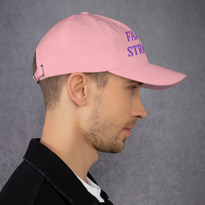 Model is wearing a Faith Strong embroidered hat – bold purple text, pink adjustable unisex cap by ReBirth Living
