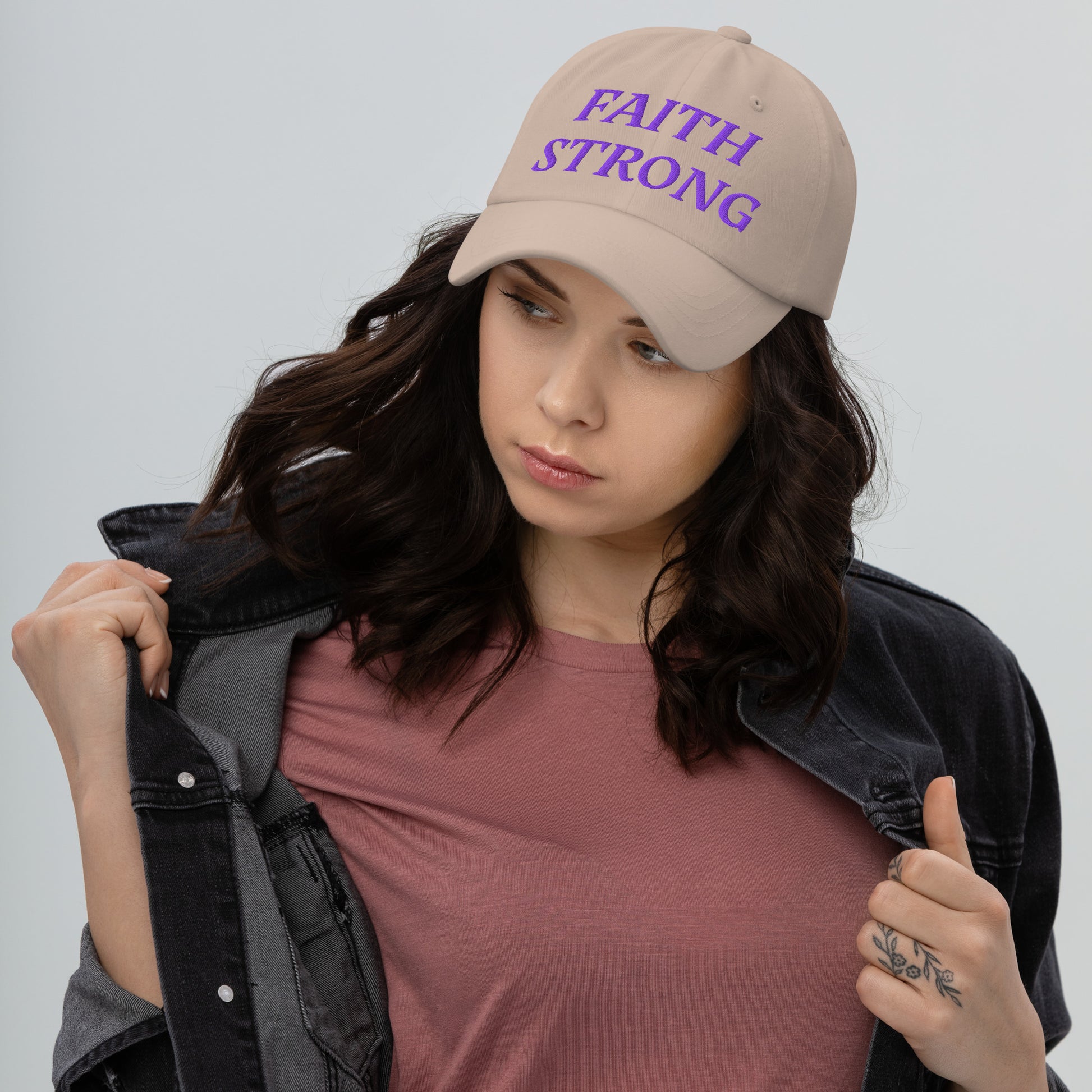 Person is wearing a Faith Strong stone cap – bold Christian statement hat with purple embroidery, adjustable unisex design by ReBirth Living