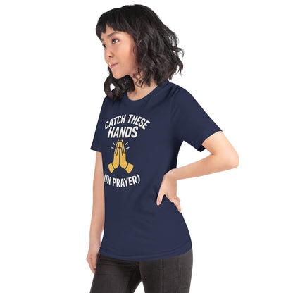 Model wearing “Catch These Hands (In Prayer)” – funny Christian t-shirt, navy, faith-based humor design with golden praying hands by ReBirth Living
