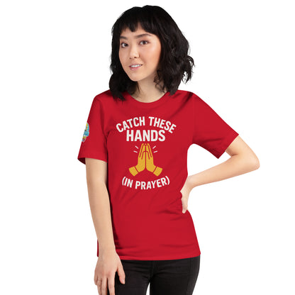 Model wearing “Catch These Hands (In Prayer)” – funny Christian t-shirt, red, faith-based humor design with golden praying hands by ReBirth Living