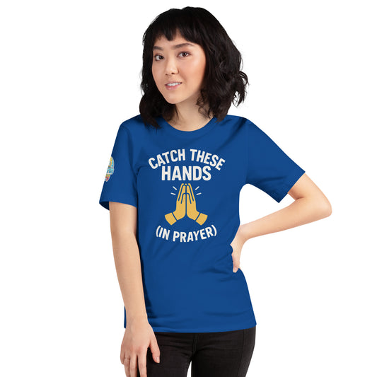 Model wearing “Catch These Hands (In Prayer)” – funny Christian t-shirt, true royal blue, faith-based humor design with golden praying hands by ReBirth Living